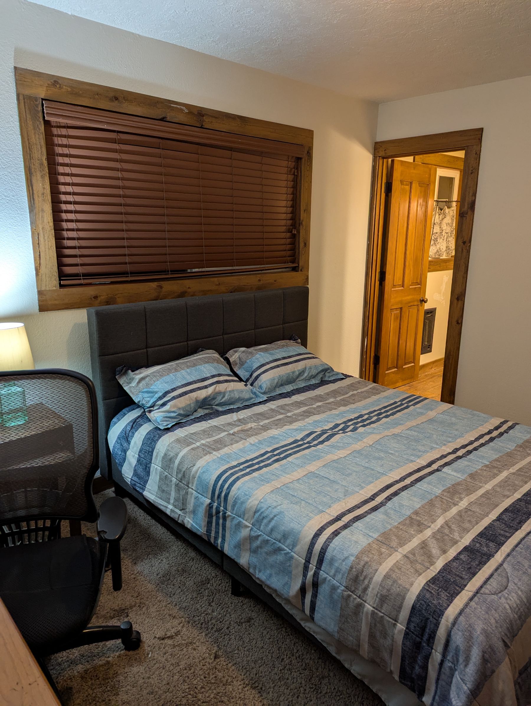 Queen bed with striped bedding and a desk workspace