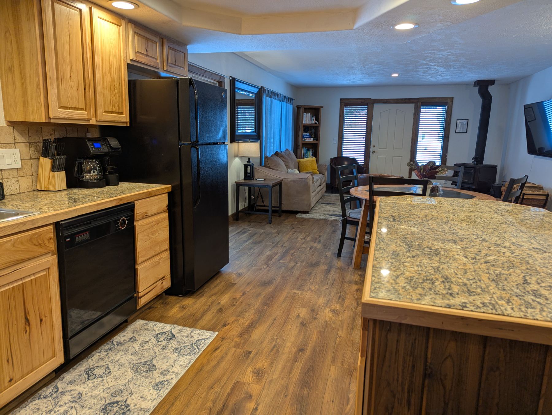 Kitchen island open to dining and living room with wood stove