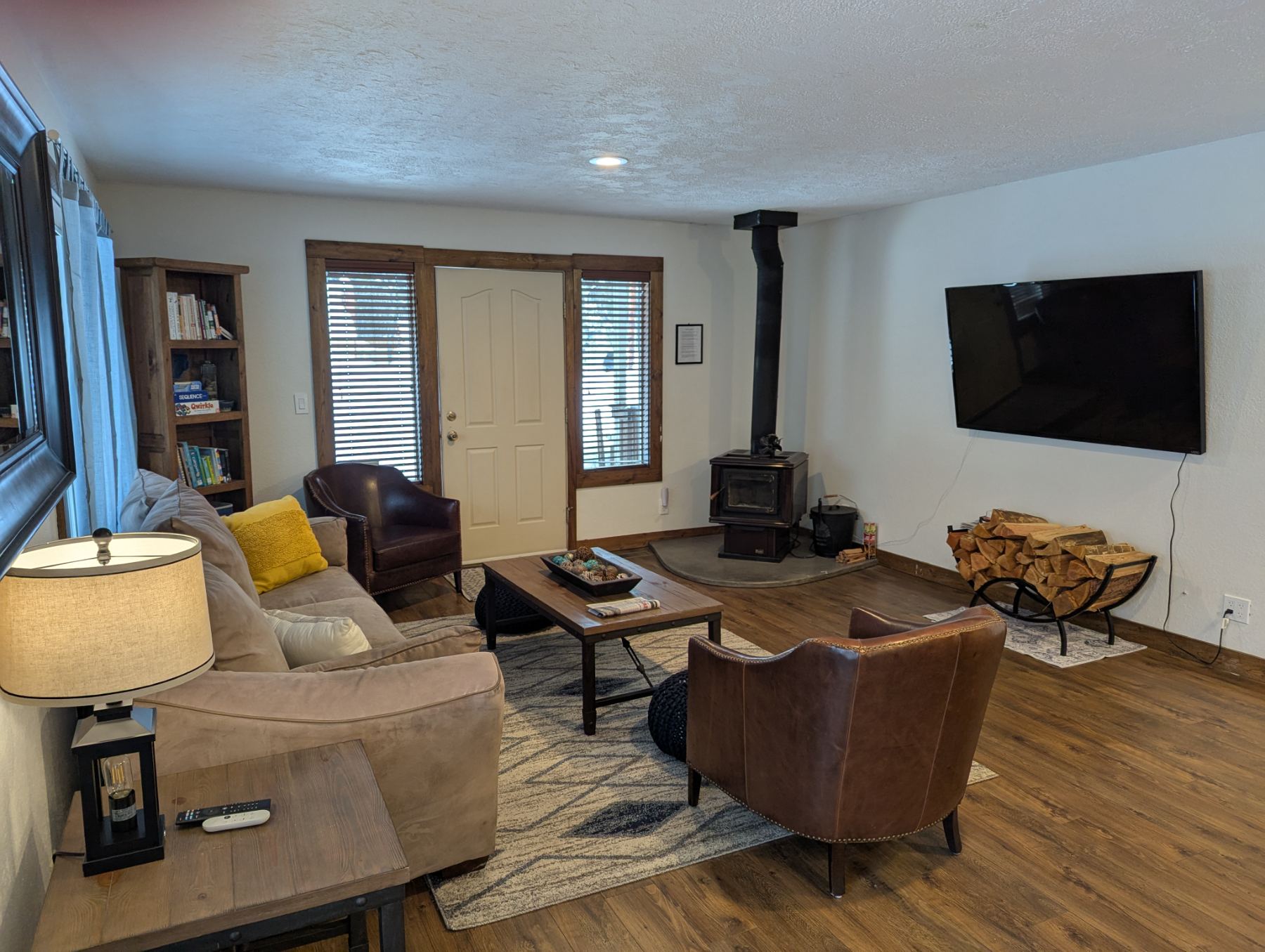 Living room with leather chairs, wood stove, and the front door